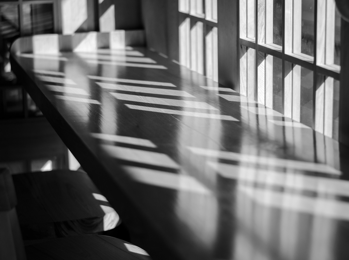 Heller Besprechungstisch mit Sonnenlicht, Unterlagen und Stift – Sinnbild für eine Führungsklausur und strategische Entscheidungen im Leitungsteam.